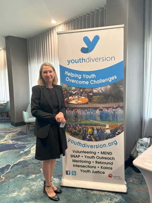 Anne Standing infront of Youth Diversion Sign wearing a black dress